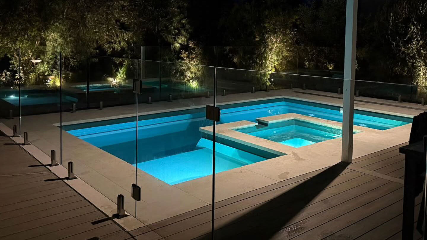 The Muse with Spa 6.10 in Shoreline A beautiful fibreglass swimming pool illuminating aquamarine colour at nighttime