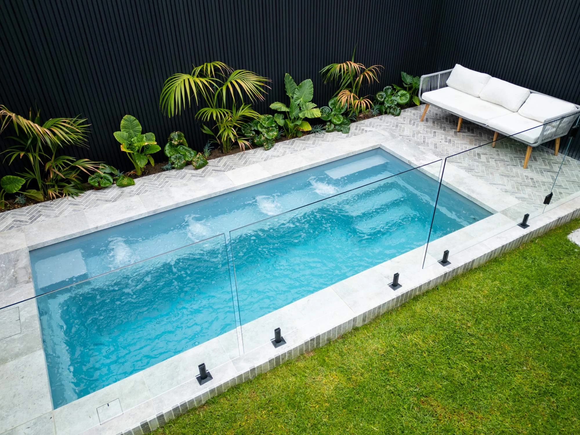 The stunning fibreglass swimming pool – The Journey – in beautiful light grey Mist colour, located in a Melbourne Bayside backyard with entry steps, bench seats, and a full-length swimming corridor.